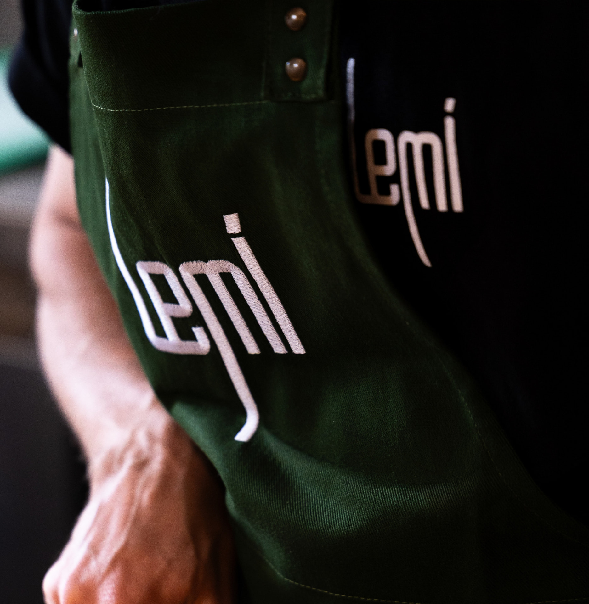Bordado branco da marca Lemi em avental verde Aprons